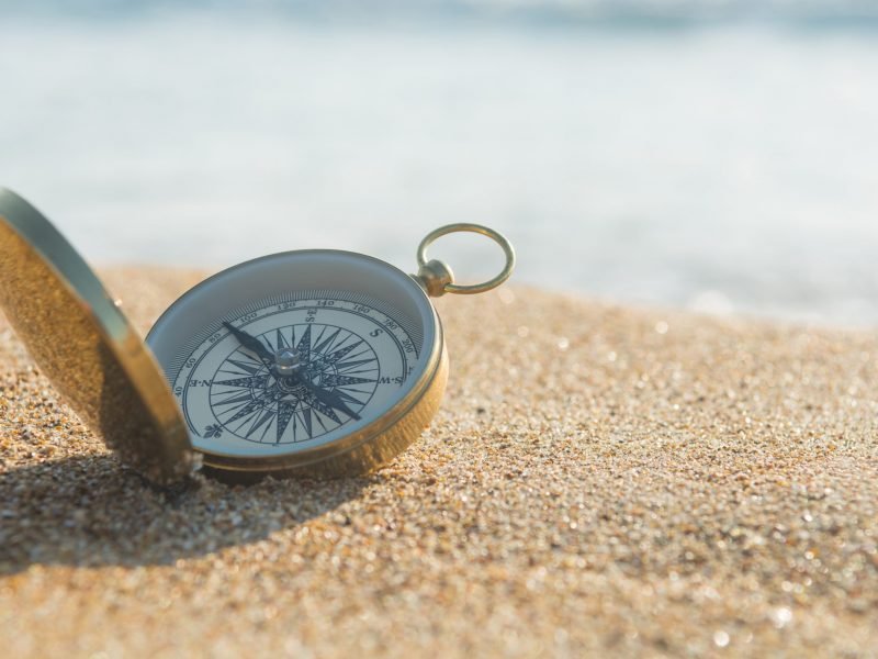 Compass on the golden sand by the sea